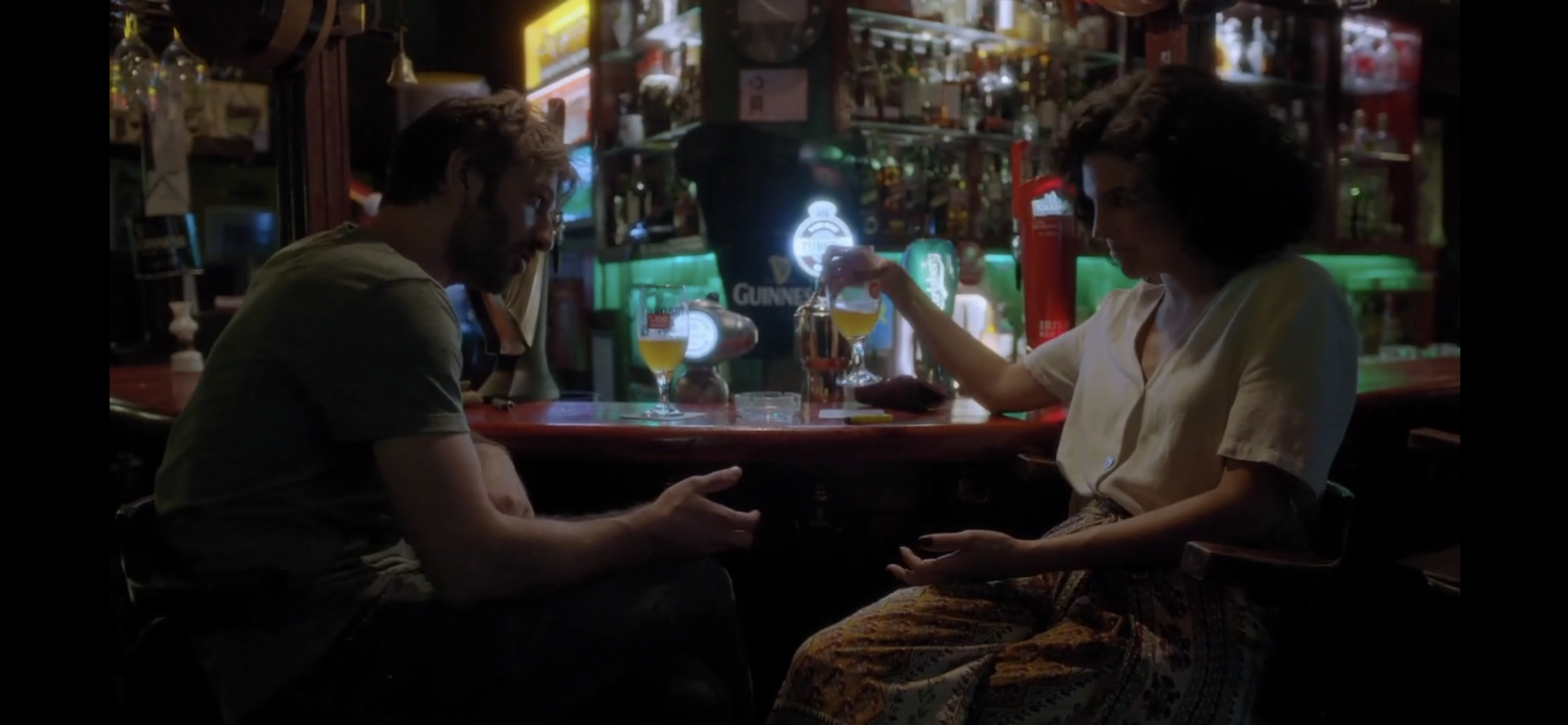 Diyalog — A woman gesturing toward a man across a bar counter.