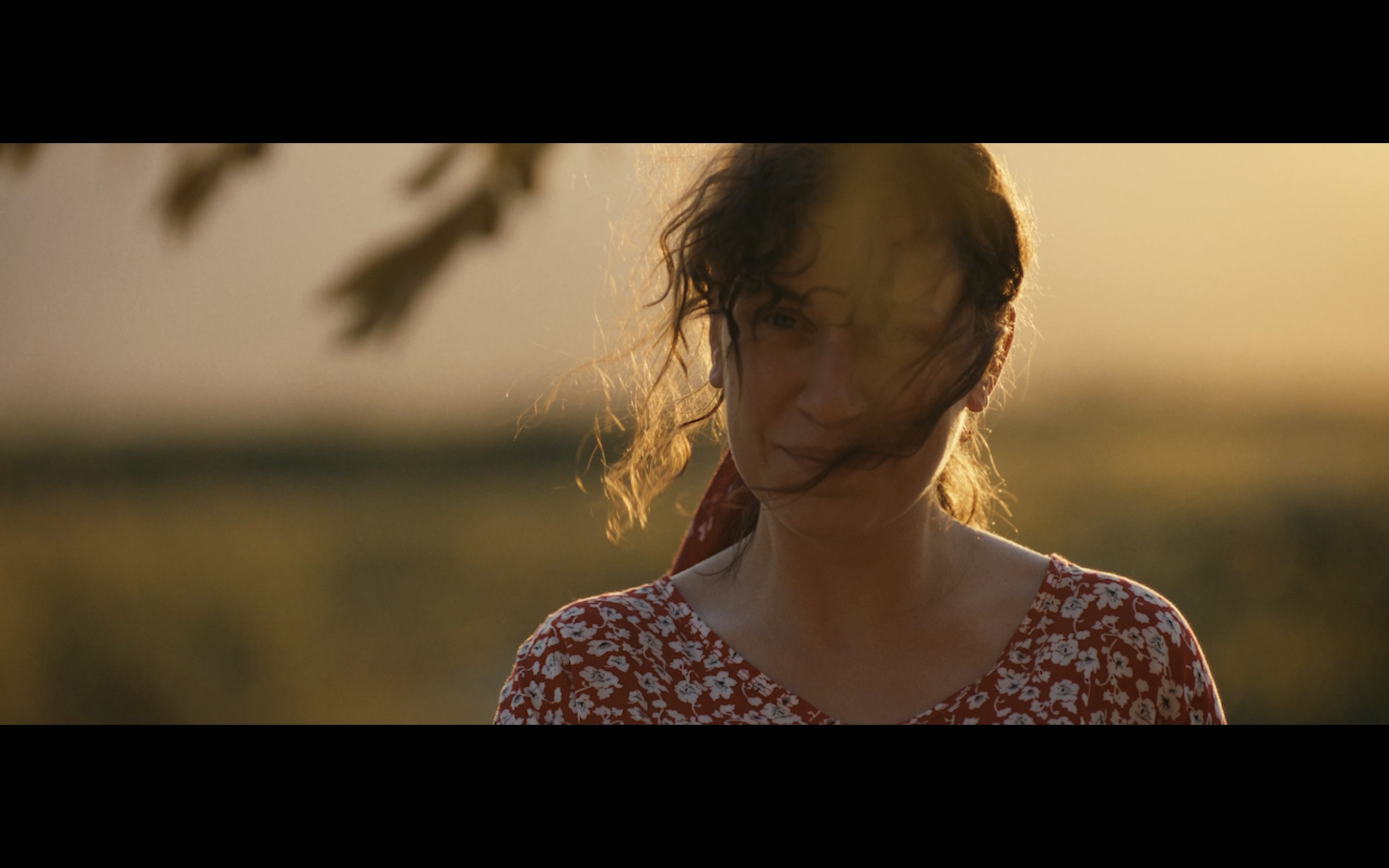 Kavanoz — A woman in a red floral dress in golden evening light.