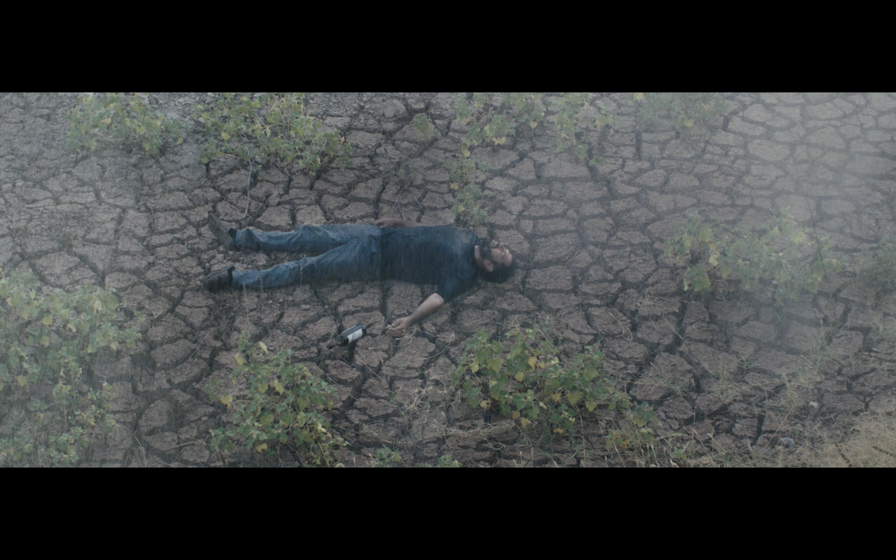 Kavanoz — Overhead view of a man lying on cracked earth.