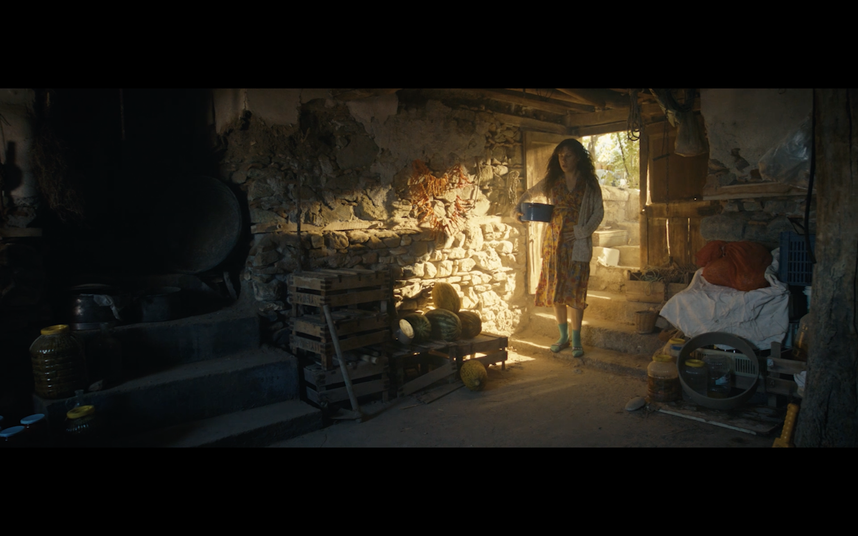 Kavanoz — A figure standing in a shaft of sunlight in a stone-walled room.