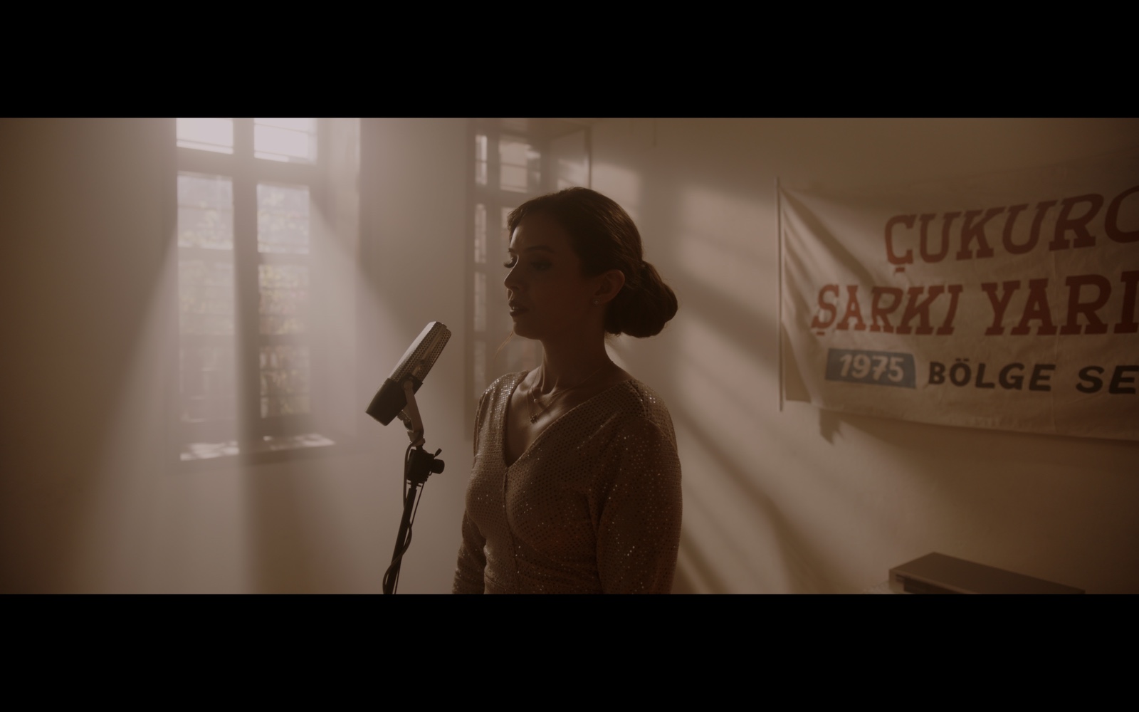 Radyo Günleri — A singer at a microphone in warm shafts of window light.